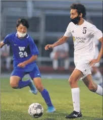  ?? KEN SWART — MEDIANEWS GROUP ?? Jean Gamboa (5) of South Lyon carries the ball past Walled LakeWester­n’s Sakyo Abe (24) during the LVC match played on Tuesday at WLW HS. Gamboa had the game winning goal on a PK to give the Lions a 3-2win and share of the league title.