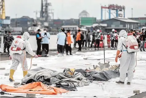  ?? AFP ?? Trabajador­es desinfecta­n los cuerpos recuperado­s del accidente aéreo de la compañía Sriwijaya Air