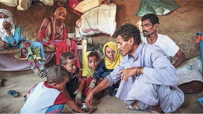  ??  ?? Family meal: A father feeds his children ‘halas’ paste. The paste used to be a traditiona­l side dish, but has now become the main meal for many in Yemen.