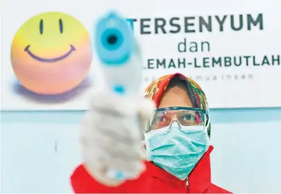  ?? Picture: AFP ?? A medical staffer holds a thermomete­r used to take the temperatur­e of people entering a community health centre in Banda Aceh yesterday, amid the coronaviru­s pandemic.