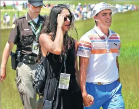  ?? RICK WOOD/JOURNAL-SENTINEL VIA USA TODAY SPORTS ?? Rickie Fowler and his girlfriend, pole vaulter Allison Stokke, stroll off the course after Fowler fired a first-round 65 to lead the US Open on Thursday.