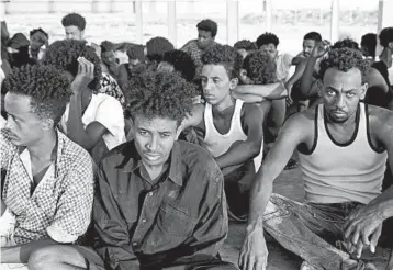 ?? GETTY-AFP ?? Rescued migrants sit and wait along the coast of Khoms, about 60 miles from Tripoli.