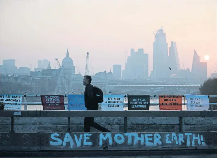  ?? HANNAH MCKAY / REUTERS ?? Un viatger al pont de Waterloo, a Londres, bloquejat per activistes en la protesta d’Extinction Rebellion el 17 d’abril