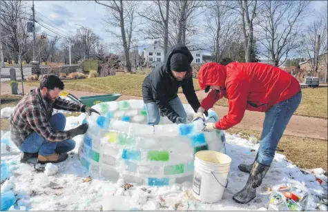  ?? KIRK STARRATT ?? James Collicutt and Nick Zamora, of Wolfville’s community developmen­t department, and bricklayer Ryan Noseworthy work on building an ice igloo.