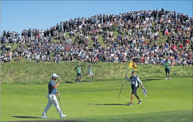  ??  ?? Jon Rahm saluda al público al aproximars­e a un green en la segunda jornada del British Open de golf que se disputa en el campo Royal St. Georges de Sandwich.