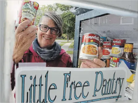  ?? CLIFFORD SKARSTEDT EXAMINER ?? Resident Margo Hudson stocks up her Little Free Pantry on Thursday at her home located at 185 Crescent St.