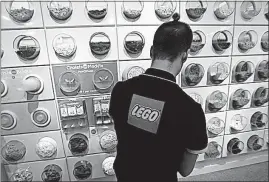  ?? [FRANCOIS MORI/THE ASSOICATED PRESS] ?? An employee sorts Legos in a flagship store in Paris. The Danish toy maker said Tuesday it will cut 1,400 jobs after reporting a decline in sales and profits in the first half of 2017.