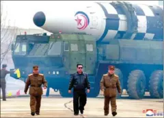  ?? AFP/KCNA VIA KNS ?? North Korean leader Kim Jong Un (centre) walks near what state media report says a new type inter-continenta­l ballistic missile, Hwasongpho-17, before its test launch in an undisclose­d location on Thursday.