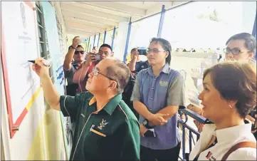  ??  ?? Uggah affixes his signature on the plaque at one of the school’s new blocks.