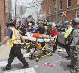  ?? AP PHOTO ?? TRAGEDY: Rescue personnel help injured people after a car, allegedly driven by James Alex Fields Jr., ran into a large group of protesters in Charlottes­ville, Va., Saturday.