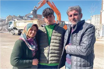  ?? The Associated Press ?? ■ Taha Erdem, 17, center, his mother Zeliha Erdem, left, and father Ali Erdem are shown on Friday next to the destroyed building where Tahan was trapped after the earthquake of Feb. 6 in Adiyaman, Turkey. Taha Erdem, a resident of southeaste­rn Turkey’s Adiyaman, is one of the hundreds of survivors pulled out of collapsed buildings after the powerful quake. He filmed himself on his phone while stuck and sandwiched between concrete in what he thought would be his last words.