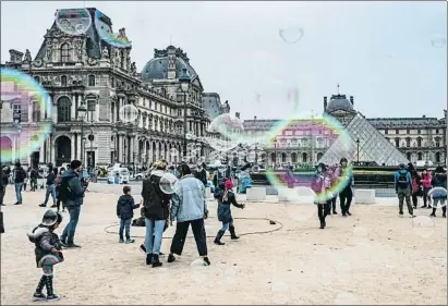  ?? -/AFP ?? Niños y adultos juegan con pompas de jabón en el exterior del Museo del Louvre de París