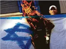  ?? Reuters ?? An activist burns a makeshift Israeli flag to protest against Egyptian Foreign Minister Sameh Shoukry’s visit to Israel, in front of the journalist­s syndicate in Cairo on Wednesday.