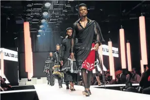  ?? OUPA BOPAPE / GALLO IMAGES ?? Male models wearing fashion designs of Tsonga women’s skirt
xibelani quietly walk the ramp in a funeral mood. David Tlale was paying tribute to his mother, who passed away in August.