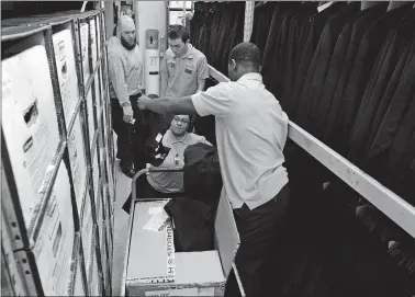  ?? DANA JENSEN/THE DAY ?? Intern Elijah LaMarre, left, hands pants to fellow intern Morgan Torres while they and intern Jason Choi, rear right, work to restock the wardrobe department at Mohegan Sun on Wednesday, with Norwich Transition Academy job coach Austin Dayger, top left, looking on.