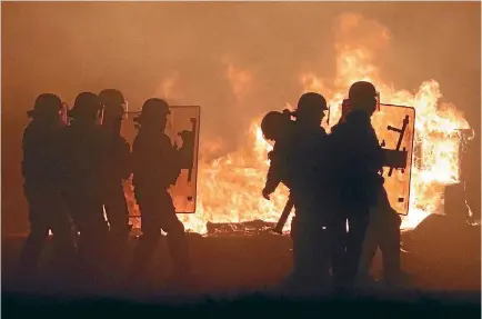  ?? PHOTO: REUTERS ?? French police are in silhouette as they pass flames on the eve of the evacuation and transfer of migrants to reception centres in France, and the dismantlin­g of the camp called the ‘‘Jungle’’ in Calais.