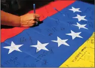  ?? CARL JUSTE/MIAMI HERALD ?? A woman places her name among others on a Venezuelan flag as they exit the polling station Sunday.