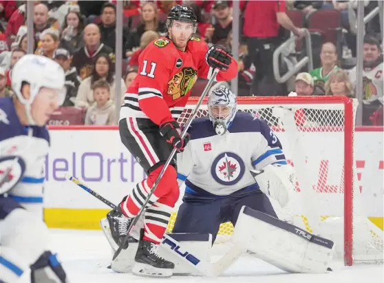  ?? ERIN HOOLEY/AP ?? Hawks forward Taylor Raddysh, skating into Jets goalie Connor Hellebuyck in the second period Friday night, has gone 24 consecutiv­e games without scoring a goal.