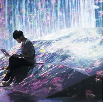  ?? PHOTO COURTOISIE ?? Un membre du collectif japonais teamLab près de l’oeuvre d’une cascade de lumière fleurie réalisée en temps réel au Mori Building Digital Art Museum, à Tokyo.