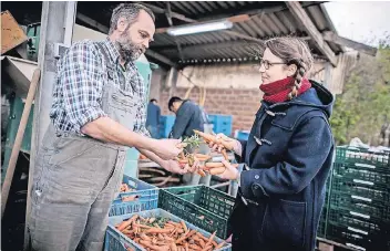  ??  ?? Heinrich Hannen, Inhaber vom Lammertzho­f in Kaarst, sucht mit Nicole Klaski Karotten aus, die sie in ihrem kleinen Supermarkt „The Good Food“in Ehrenfeld verkaufen kann.