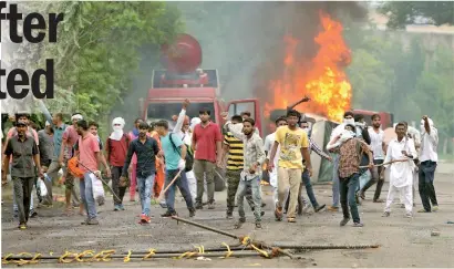  ??  ?? Supporters of Indian religious leader Gurmeet Ram Rahim Singh throw stones at security forces next to burning vehicles during clashes in Panchkula on August 25, 2017. AFP / Money Sharma