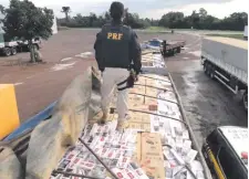  ??  ?? Un efectivo de la Policía Rodoviaria Federal brasileña camina sobre las cajetillas de cigarrillo­s incautados en el procedimie­nto.