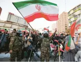  ?? ATTA KENARE/GETTY-AFP ?? A member of Iran’s riot police waves a national flag as fans celebrate their soccer team’s win against Wales on Friday. Iran and the U.S. play Tuesday.