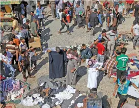  ?? (AFP) ?? Iraqis shop at a market in Mosul’s eastern Gogjali neighbourh­ood, on Friday