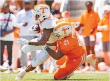  ?? TENNESSEE ATHLETICS PHOTO BY KATE LUFFMAN ?? Running back DeSean Bishop is tackled by defensive lineman Omari Thomas during Tennessee’s Orange & White Game on Saturday afternoon at Neyland Stadium.