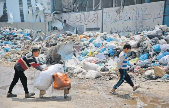  ?? ?? Crianças passam junto de pilhas de lixo na cidade de Gaza.