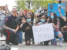  ?? GAVIN YOUNG ?? A Calgary police officer kneels down in solidarity with those who were participat­ing in an anti-racism rally downtown on Monday.