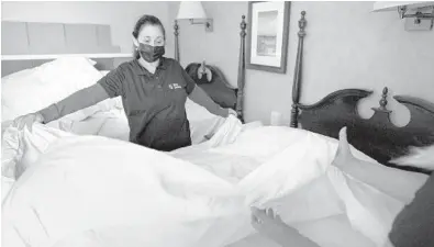  ?? STEVEN SENNE/AP ?? Hotel workers Miriam Mattos, left, and Marilene Souto, not pictured, make a bed at Red Jacket Beach Resort in South Yarmouth, Mass., on Cape Cod. Hiring challenges could force tourist destinatio­ns to curb services just as they’re eyeing a bounce-back summer.