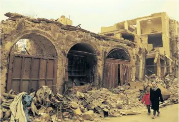  ?? JOSEPH EID/GETTY IMAGES ?? Syrian girls walk past destroyed buildings during a sandstorm in the once rebel-held Bab al-Nasr neighbourh­ood in the old part of Aleppo on Friday.