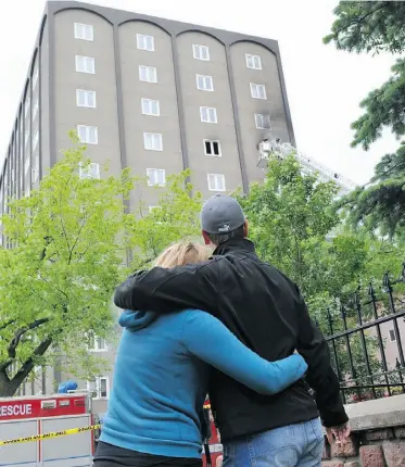  ?? SHAUGHN BUTTS/ EDMONTON JOURNAL ?? Residents of a nearby building watch firefighte­rs battle the highrise fire which claimed the lives of Don Kohlman, 46, and his daughter Jaqueline, 5, on Father’s Day.