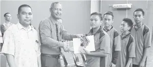  ??  ?? ABDULLAHSH­IP diiringi Mohammad Malan (kiri) menyampaik­an hadiah kepada pemain regu SMK Beluran, juara bawah 15 tahun.