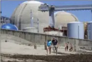  ??  ?? In this June 30, 2011, file photo, beach-goers walk on the sand near the San Onofre nuclear power plant in San Clemente, Calif. Parts and machinery from the closed nuclear generating facility, which has been closed since 2012, are going on the auction...