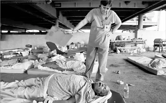  ??  ?? Nurse Mary Jo D’amico fans a patient in the Memorial Medical Centre garage as they wait for a rescue helicopter three days after Katrina struck. On Monday, 45 bodies were found at the centre