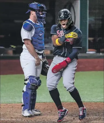  ?? Robert Gauthier Los Angeles Times ?? DODGERS CATCHER WILL SMITH, left, looks on as Atlanta’s Ronald Acuña Jr. scores one of the Braves’ four ninth- inning runs at Globe Life Field, where the crowd attendance was an announced 10,700.