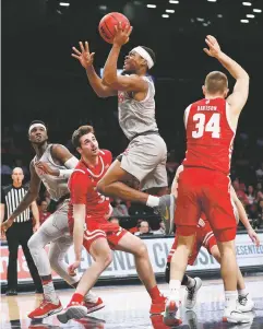  ?? KATHY WILLENS/ASSOCIATED PRESS ?? New Mexico guard JJ Caldwell, center, shoots as Wisconsin forward Nate Reuvers, left, and guard Brad Davison watch from the floor in the second half of Tuesday’s game in the Legends Classic, at Barclays Center in New York. The Lobos won 59-50.