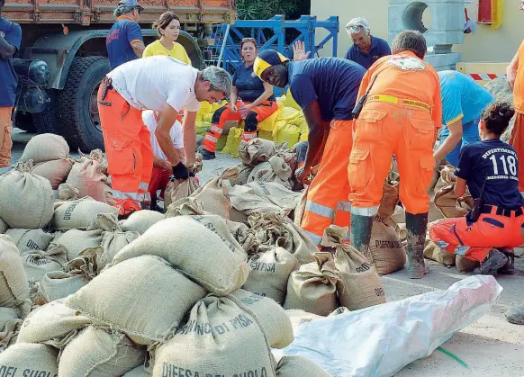  ??  ?? I volontari della protezione civile con i sacchi di sabbia che sono stati distribuit­i ieri nelle zone di Livorno a rischio alluvione
