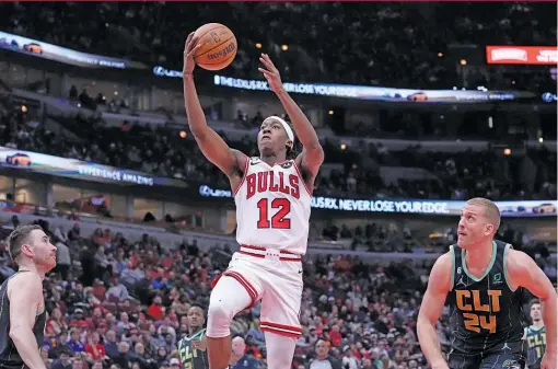  ?? AP ?? Bulls guard Ayo Dosunmu glides in for a layup between the Hornets’ Gordon Hayward (left) and Mason Plumlee. He led the Bulls with 22 points Thursday.