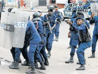  ??  ?? TENSE STAND-OFF: Policemen react after a protester threw a stone from the Notre Dame Cathedral compound in Kinshasa yesterday