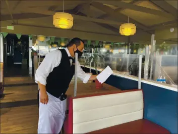  ?? PHOTO COURTESY OF OLD FISHERMAN’S GROTTO ?? Esteban Magallanes cleans the booths at Old Fisherman’s Grotto in anticipati­on of the restaurant reopening soon.