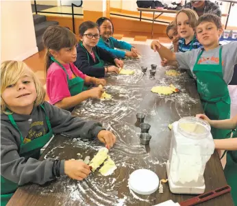  ?? COURTESY COOKING ROUND THE WORLD ?? Left: School-age naturalist­s explore wildlife with a magnifying glass as part of the Bay Area Discovery Museum’s Outdoor Explorers camp. Right: Kids prep food at the Cooking Round the World camp, where they study a new country every day and then make a...