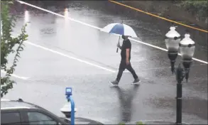  ?? Tyler Sizemore / Hearst Connecticu­t Media ?? A pedestrian crosses the street with an umbrella as Tropical Storm Henri hits Stamford on Sunday.