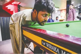  ?? AAMIR QURESHI/AFP/ GETTY IMAGES ?? Muhammad Ikram, born without arms, lines up a shot at a snooker club in Samundri, Pakistan, last month. Hitting the cue ball with his chin, he has won several prizes in local tournament­s.