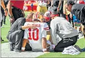  ?? PETER AIKEN — GETTY IMAGES ?? San Francisco 49ers quarterbac­k Jimmy Garoppolo is examined by head coach Kyle Shanahan and the team training staff after suffering a knee injury Sunday.