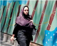  ?? AFP ?? A woman walks by a mural painting on the wall of the former US embassy in the Iranian capital Tehran on Tuesday. —