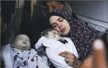  ?? Hatem Ali Associated Press ?? RANIA ABU ANZA cradles her twins, who were killed Saturday in an Israel strike that hit a house in Rafah, Gaza Strip. Her husband and at least 11 other relatives also died, survivors and local health officials said.