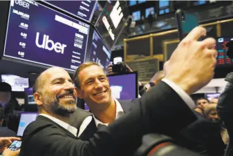  ?? Richard Drew / Associated Press ?? Uber CEO Dara Khosrowsha­hi (left) and board member Ryan Graves celebrate their IPO.